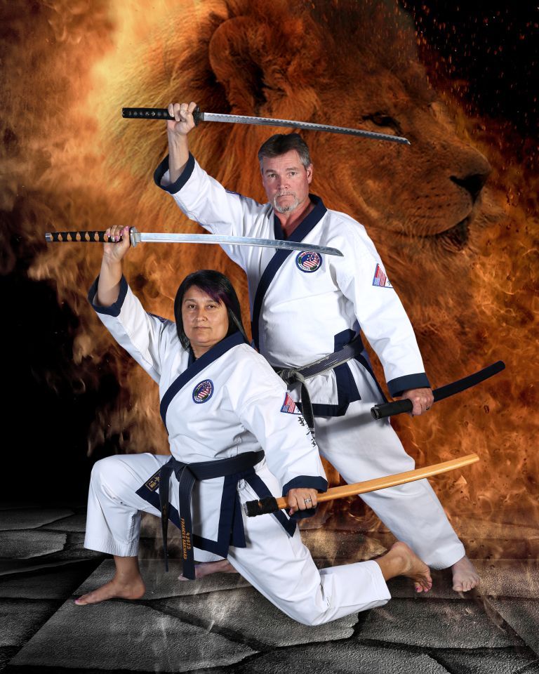 A man and a woman are holding swords in front of a lion