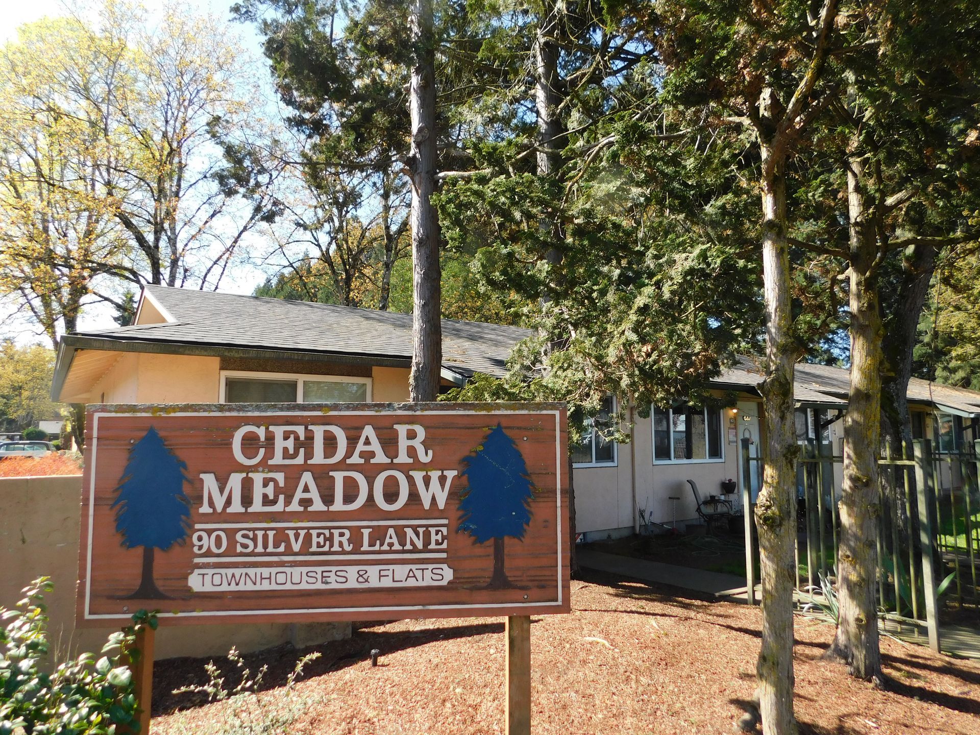 Sign for Cedar Meadow apartments at 90 Silver Lane, with a tan building in the background.