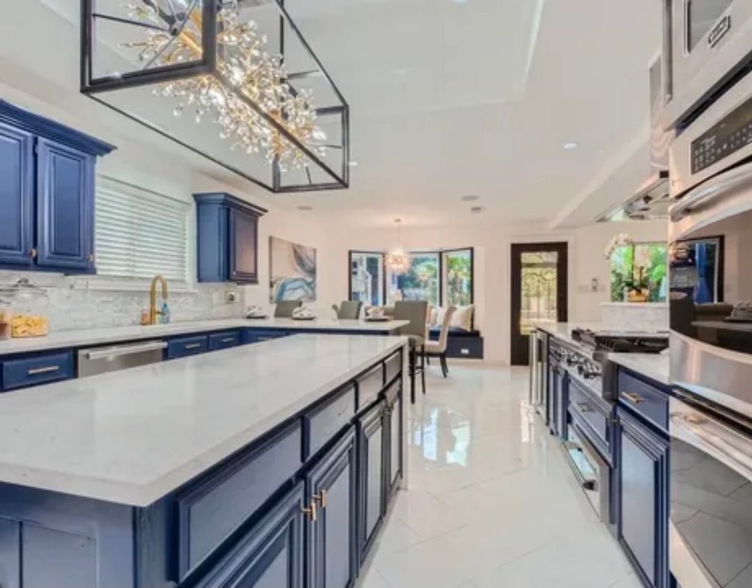 Bright modern kitchen with navy cabinets, large island, white countertops, and pendant lights