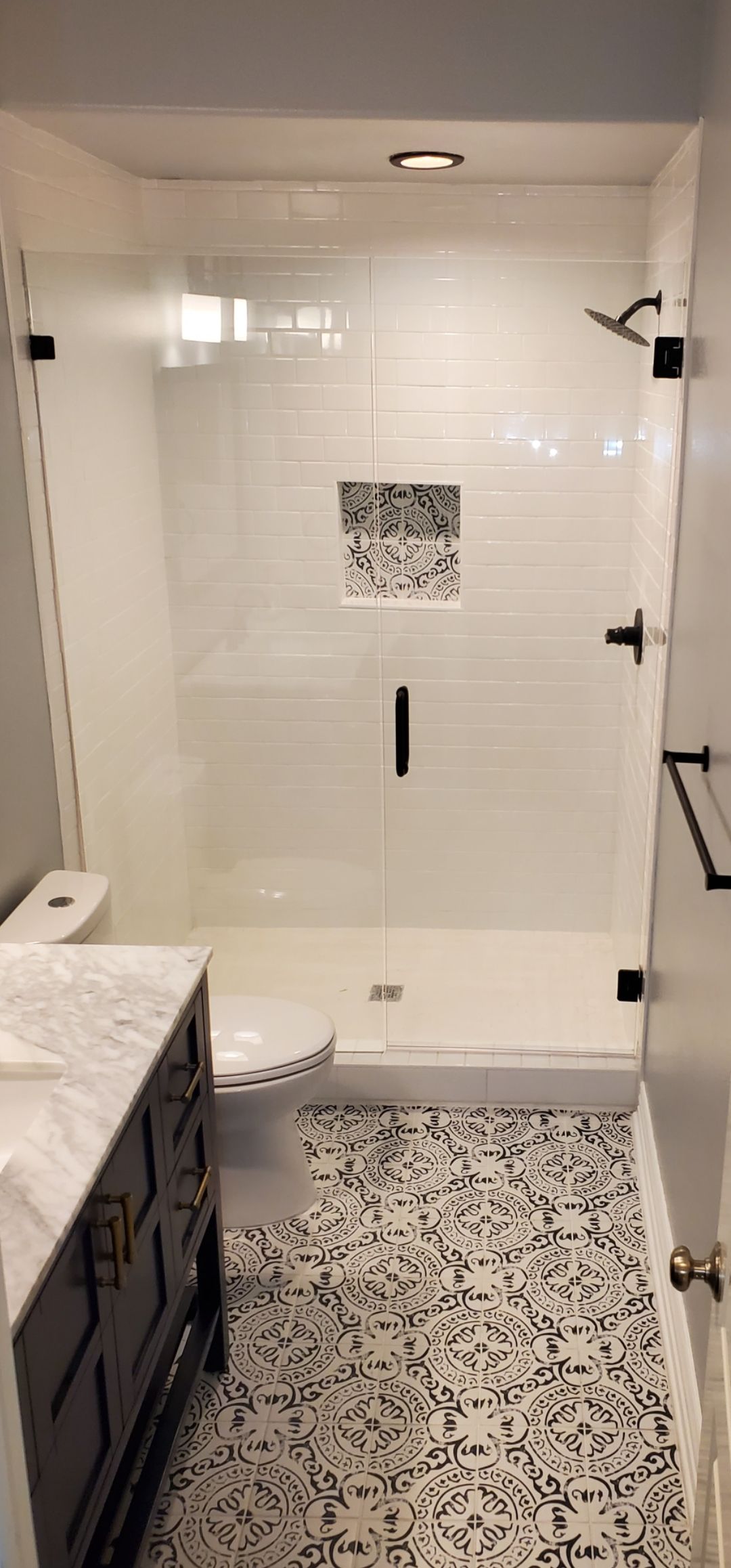 Modern bathroom with white shower, patterned tile floor, and dark vanity sink