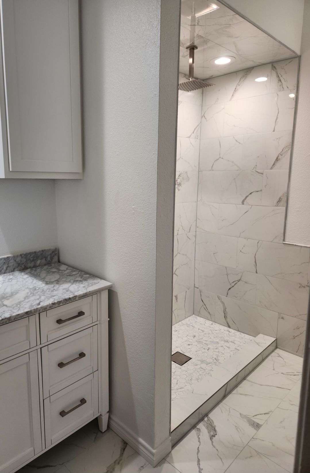 Bathroom vanity next to a glass shower with white tile and a built-in bench