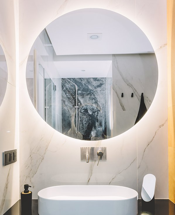 A bathroom with a sink , mirror and oval mirror.