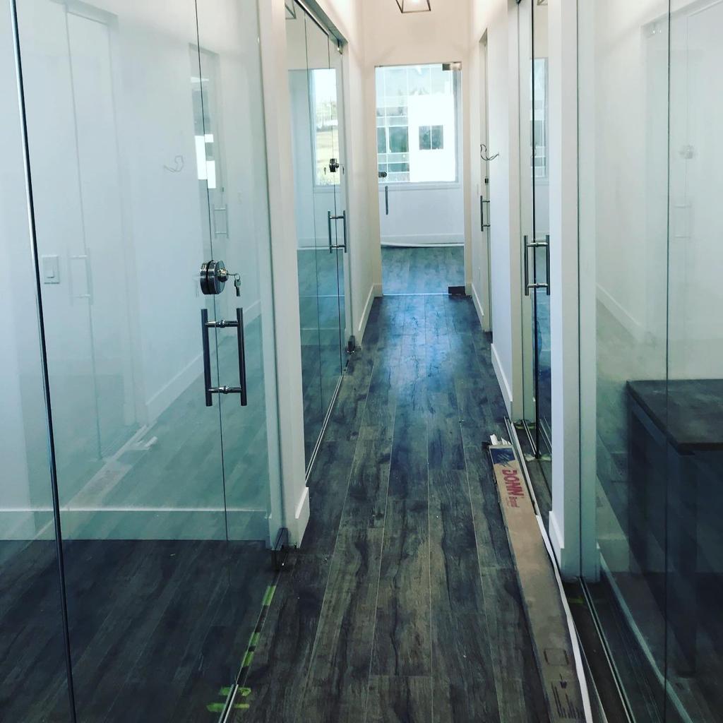 A long hallway with office glass doors and wood floors