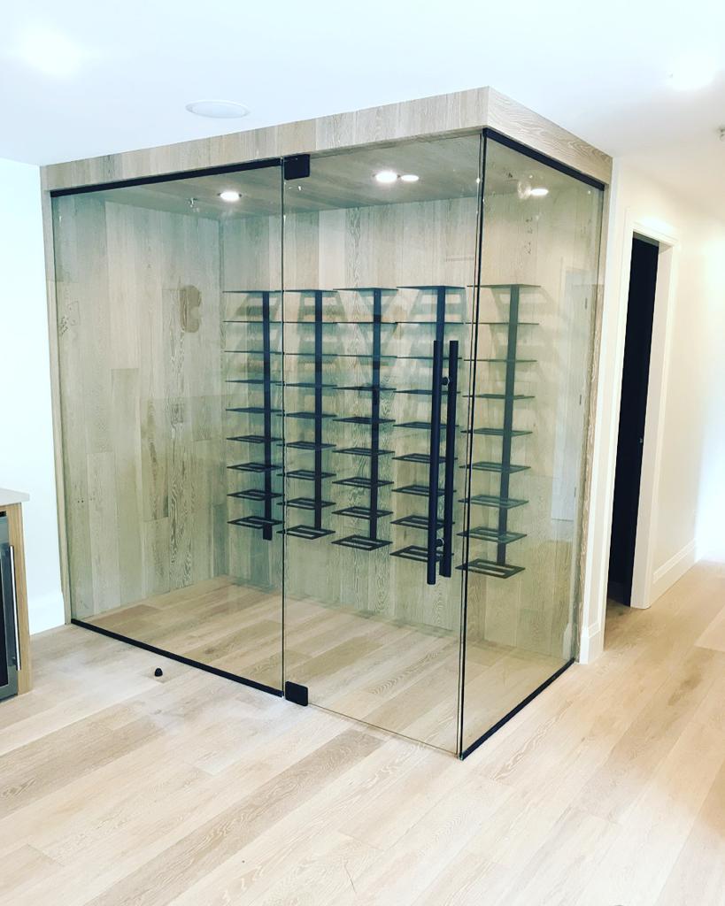 A wine cellar with glass doors and shelves filled with wine bottles.