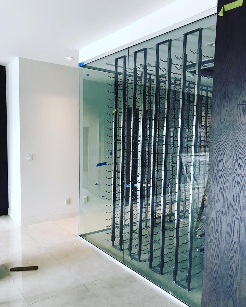 A room with a glass wall and a wine rack.