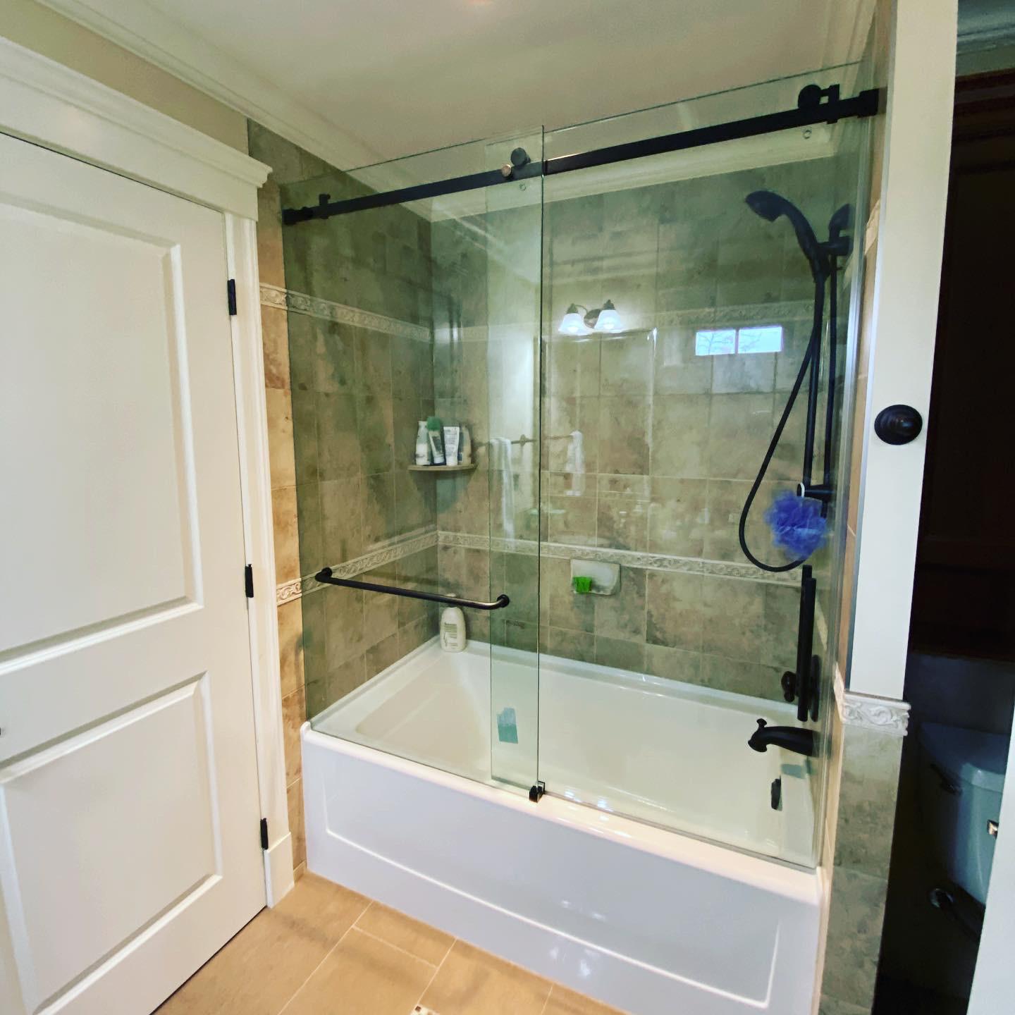 A bathroom with a bathtub and a shower with a sliding glass door.