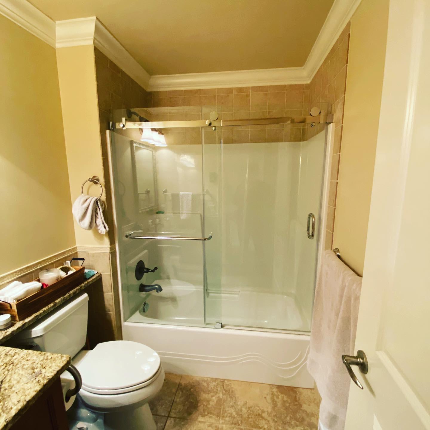 A bathroom with a toilet a tub shower door