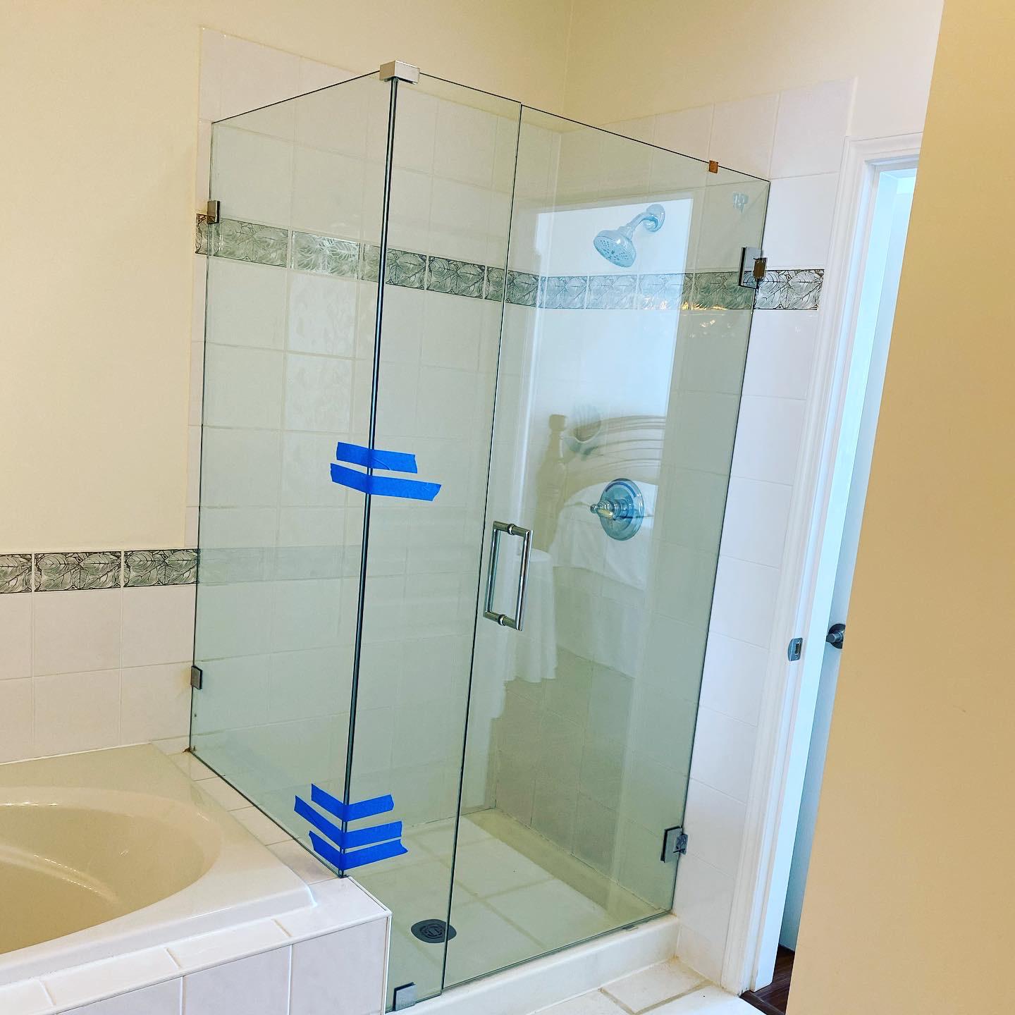 A bathroom with a corner glass shower door and a bathtub.