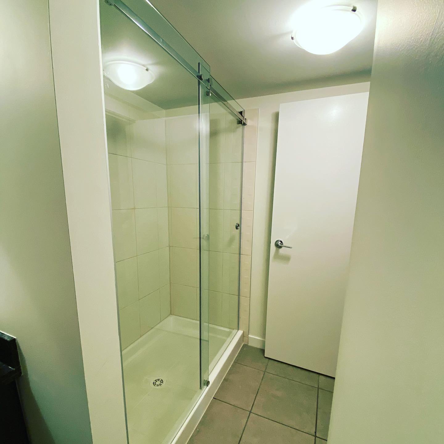 A bathroom with a sliding glass shower door and a white door.