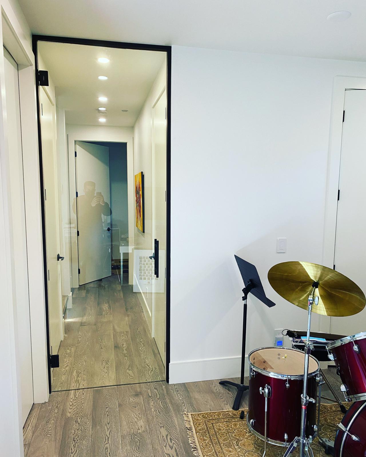 A drum set is sitting in a room next to a doorway.