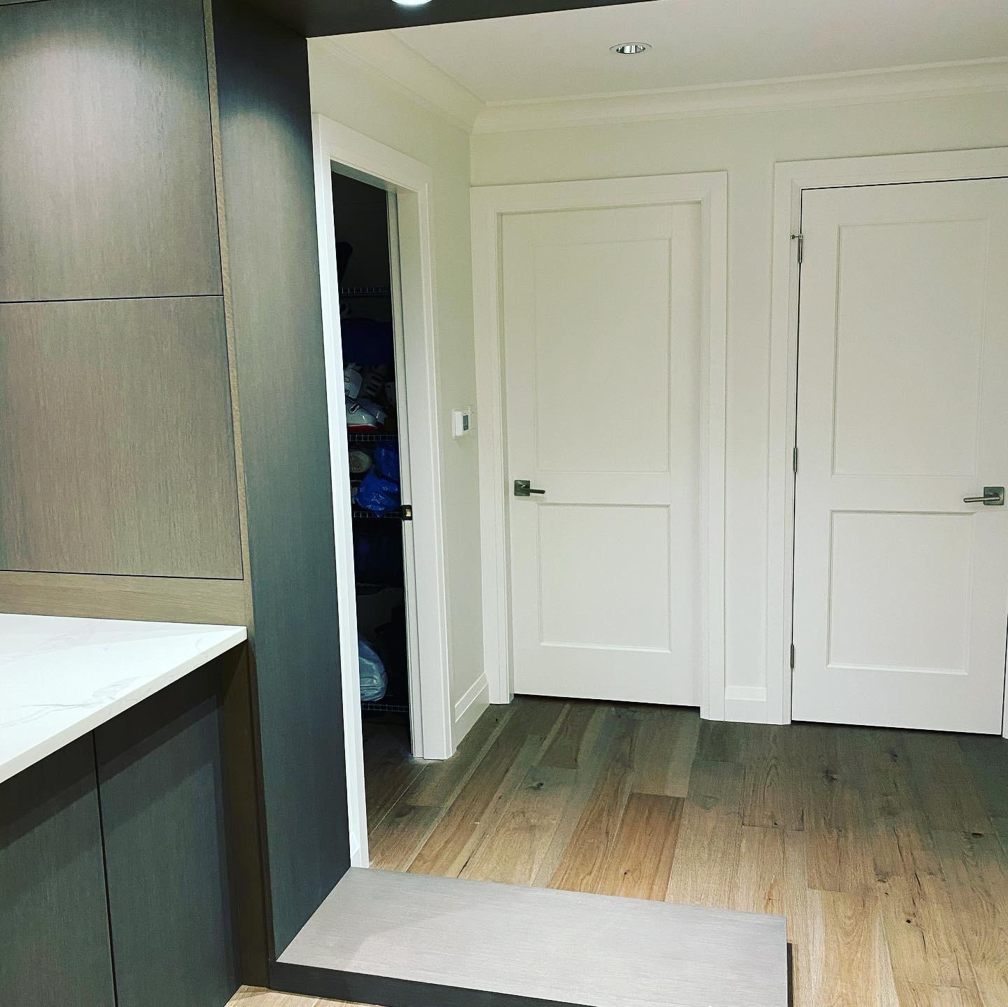 A hallway with hardwood floors and white doors wine cellar