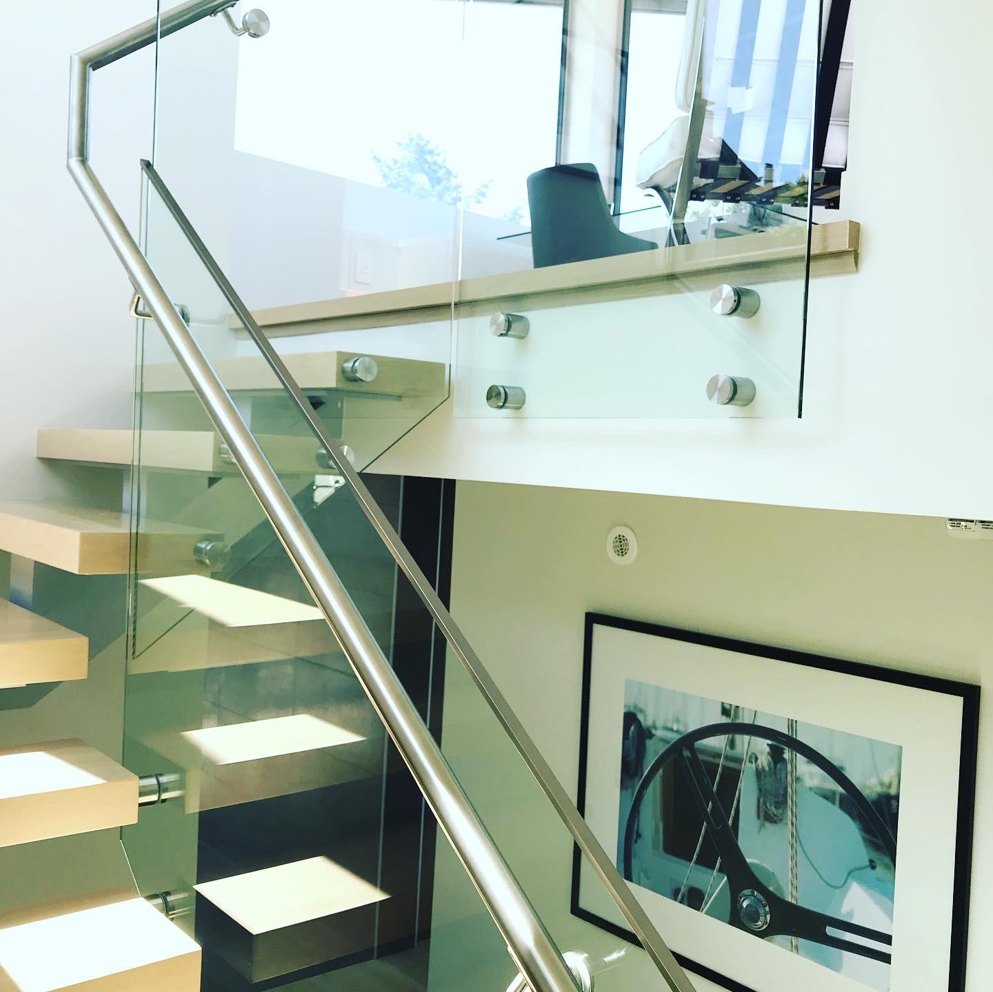A staircase with a glass railing and a picture on the wall