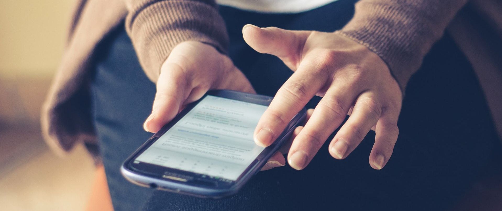 A woman is holding a cell phone in her hands.
