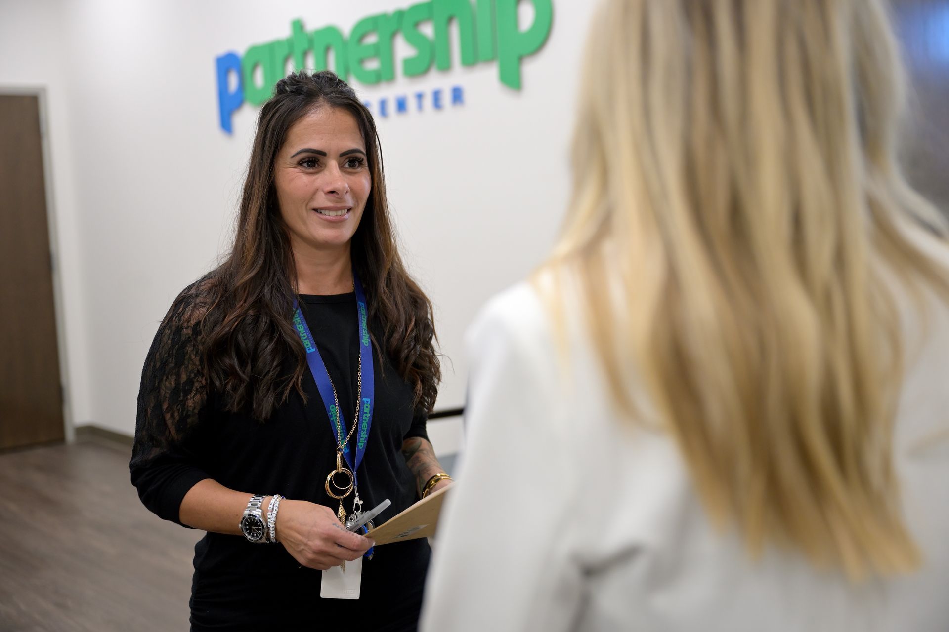 Woman in black shirt speaks to another woman in an office setting with