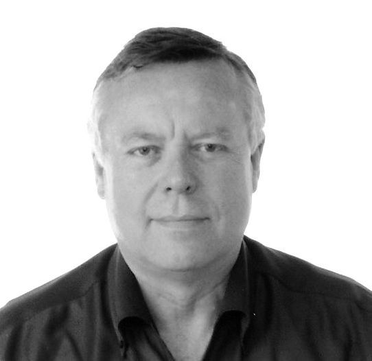 Man with short hair in a dark shirt looking towards the camera.