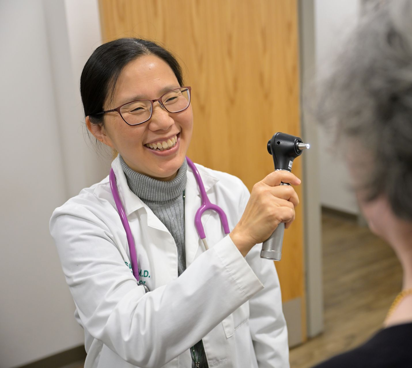 Woman in glasses and white coat, smiling, professional headshot.