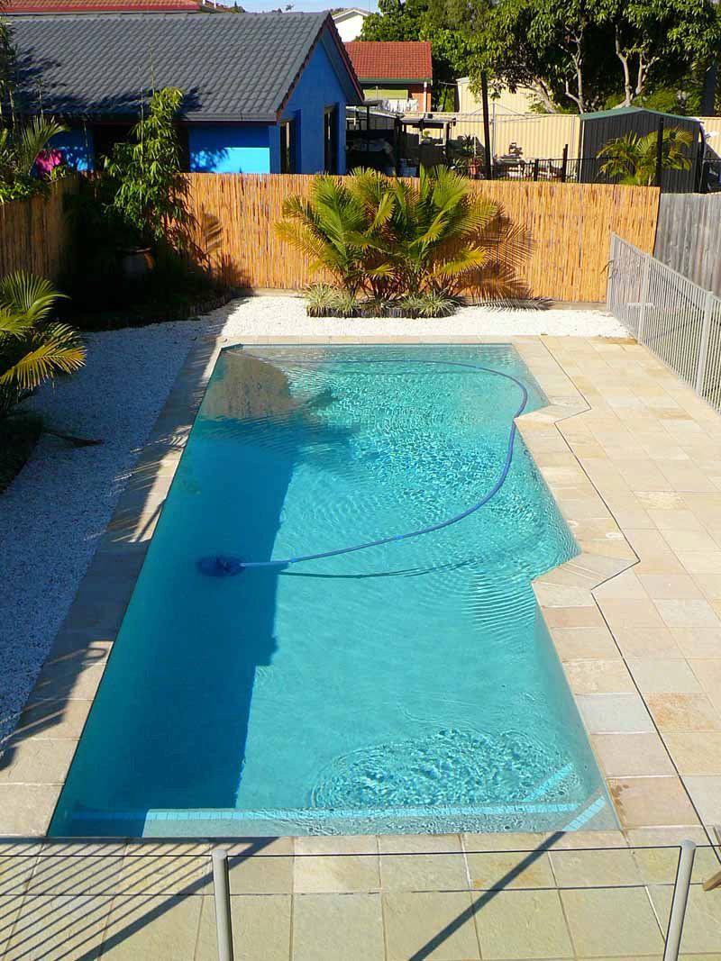 Rectangular Turquoise Pool in a Backyard, Surrounded by Stone Tiles and a Bamboo Fence — Banora Pools in Currumbin, NSW