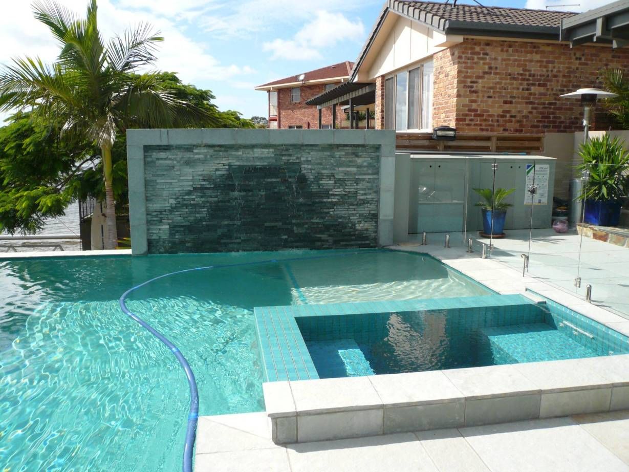 A Modern Pool With a Waterfall Feature in a Backyard Setting With a House — Banora Pools in Currumbin, NSW