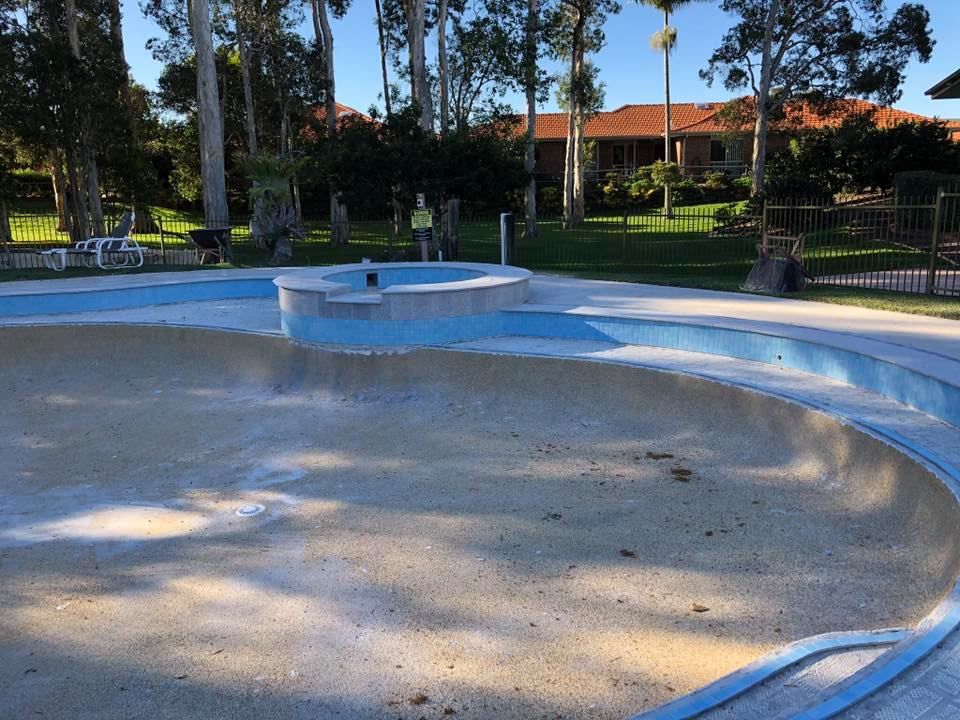 Empty, Drained Swimming Pool in a Park, With Blue Trim and a Central Platform — Banora Pools in Kingscliff, NSW