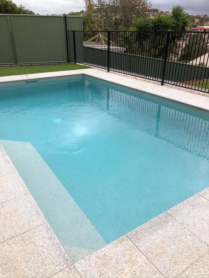 A rectangular swimming pool filled with turquoise water, steps, and surrounding light-colored paving stones. — Banora Pools in Tweed Heads South, NSW