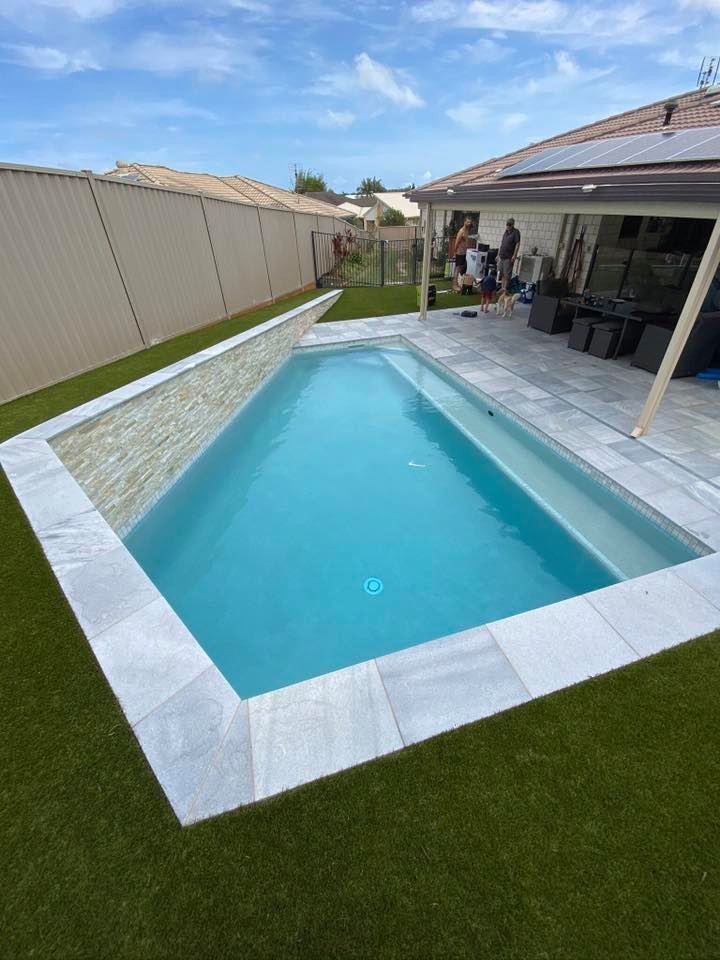 Rectangular Pool With Blue Water, Surrounded by Stone and Green Artificial Grass, in a Backyard — Banora Pools in Banora Point, NSW