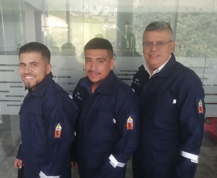 Personas con trajes de protección y máscaras con dos personas con vestimenta normal dentro de una habitación.