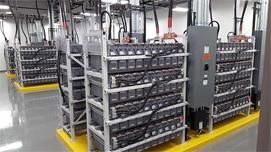 Bastidores de baterías en una instalación, con baterías grises y negras sobre plataformas amarillas.