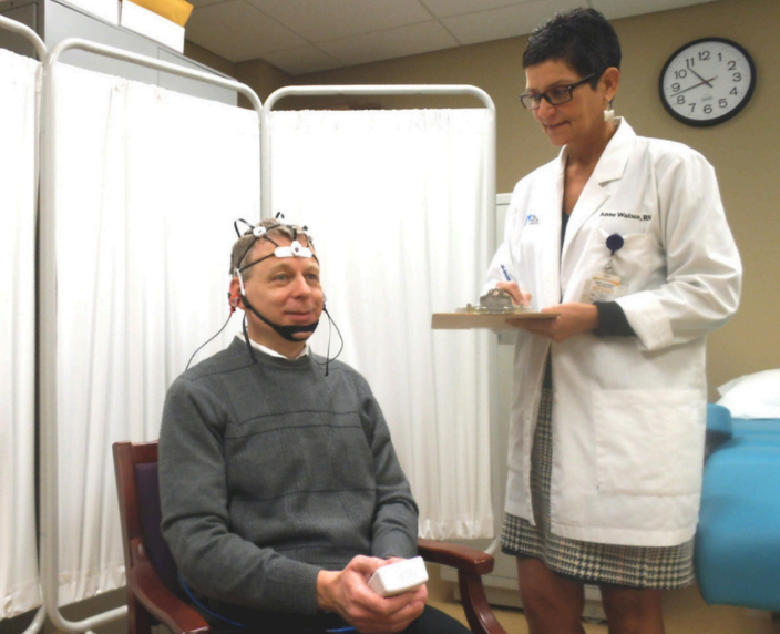 Patient undergoing a medical test while a clinician takes notes in a clinic room.