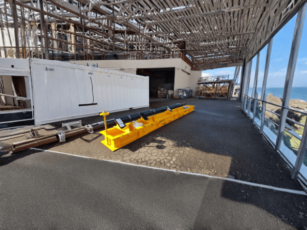 A long yellow industrial beam sits on a paved patio.