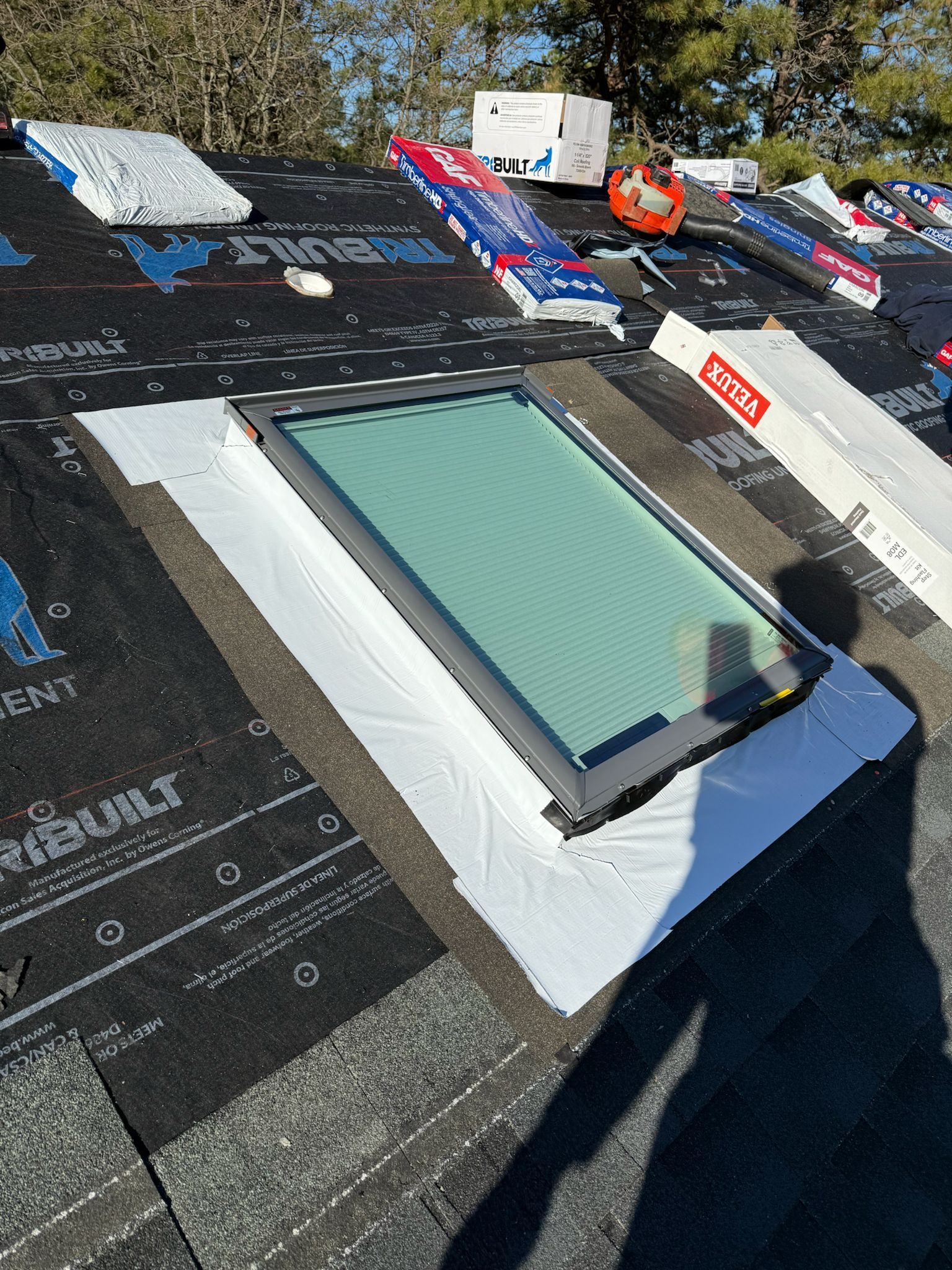 Flat roof with a skylight under construction, surrounded by roofing membrane and materials.
