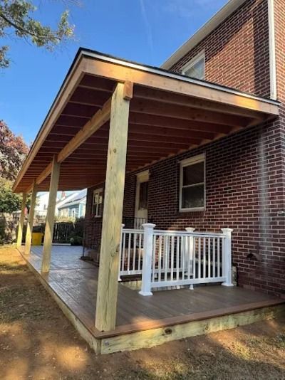 Covered wooden porch on a brick house with white railing and deck steps