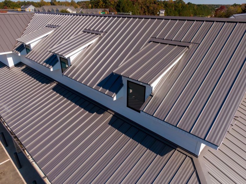 Metal roof with skylights and dormer windows on a building under a clear sky