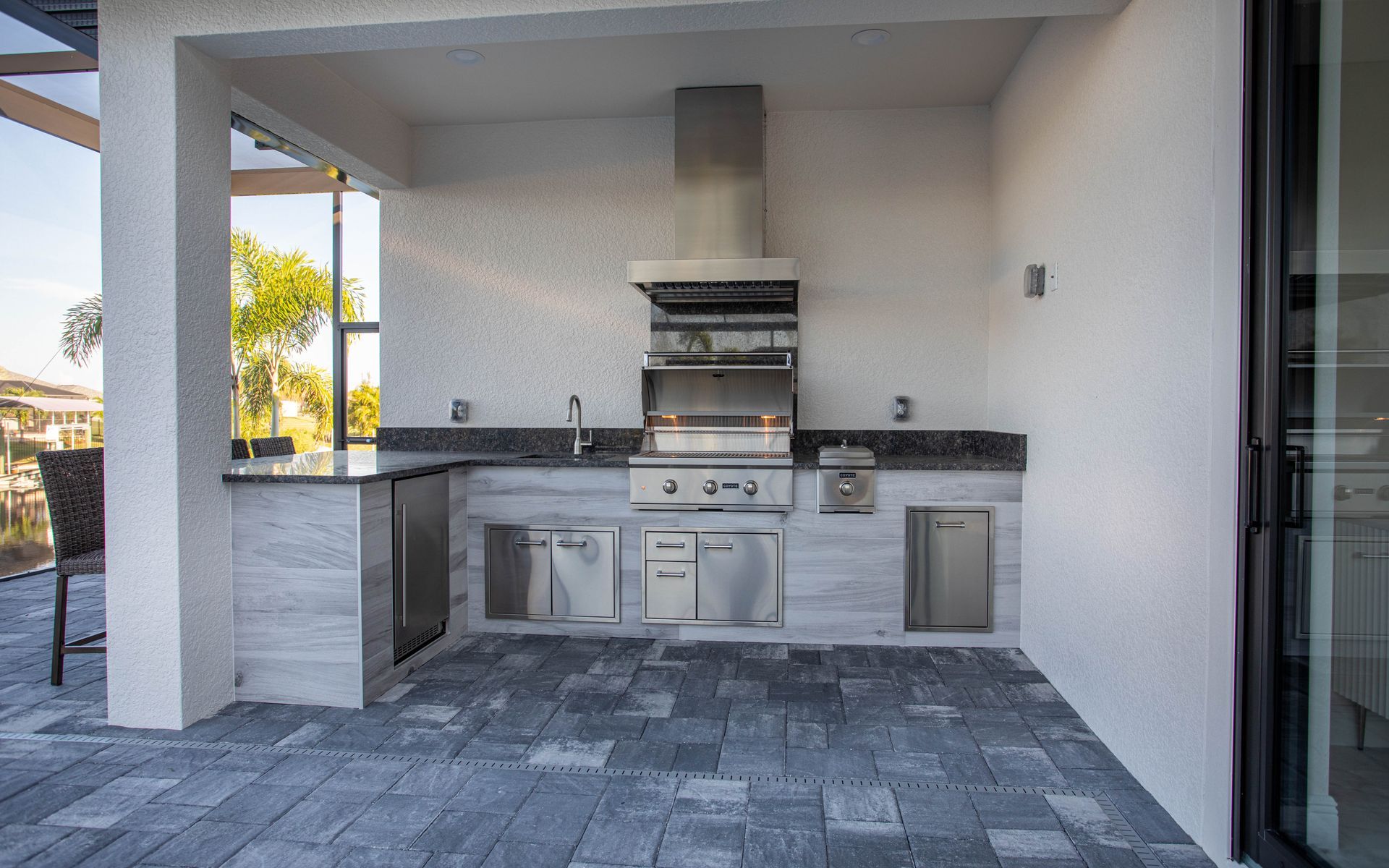 L Shape Outdoor Kitchen, Granite countertop, Twin Eagles Grill, Delta Heat Inserts, Fridge, grey wood look tile Estero FL