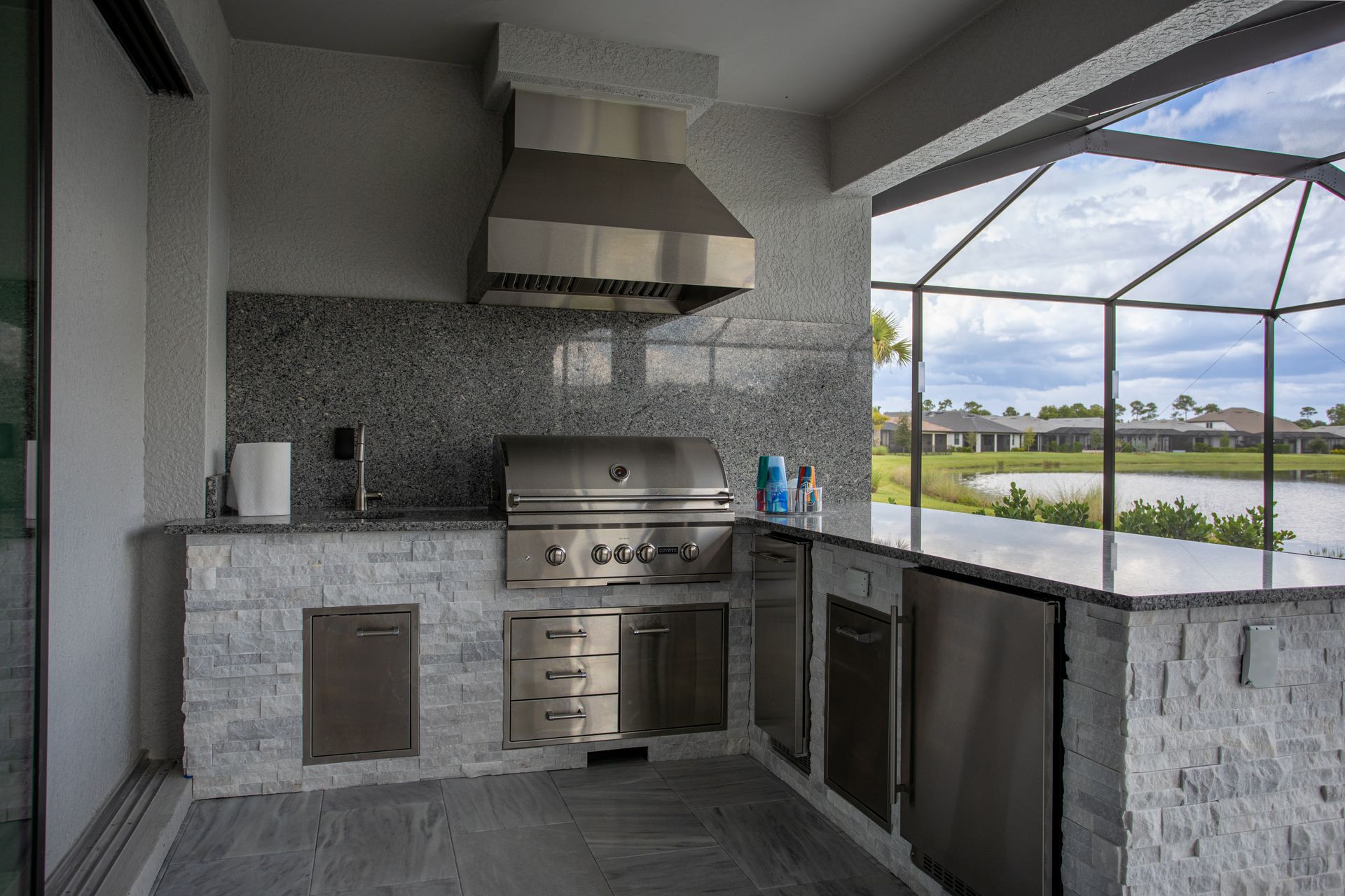 L Shape Outdoor Kitchen , Granite countertop, brown wood look tile, teal backsplash, Delta Heat Inserts, Naples FL