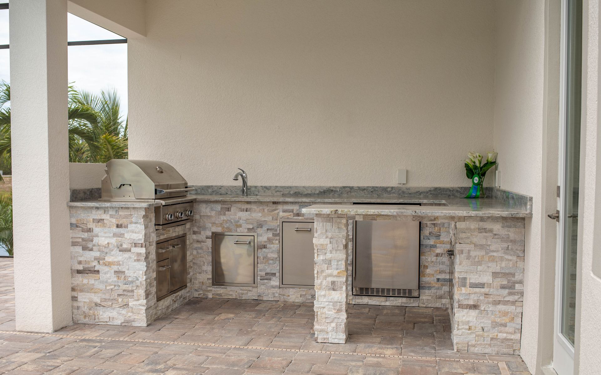 J shape outdoor kitchen, stacked stone, grill, storage, tan and white, simple, matches house color, Cape Coral FL