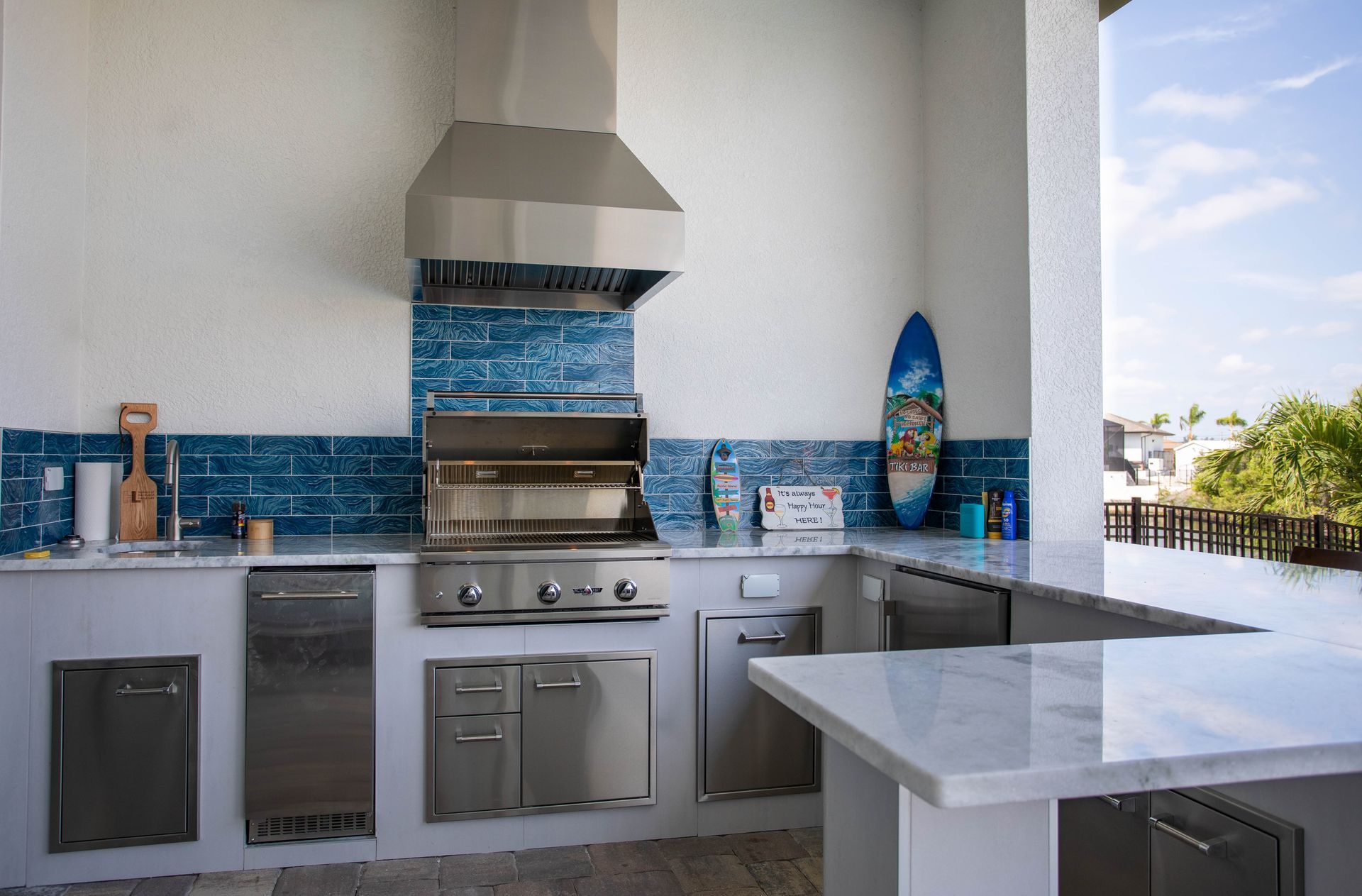 White tile outdoor kitchen, blue backsplash, bar seating, grill, hood, stainless steel, storage Naples FL