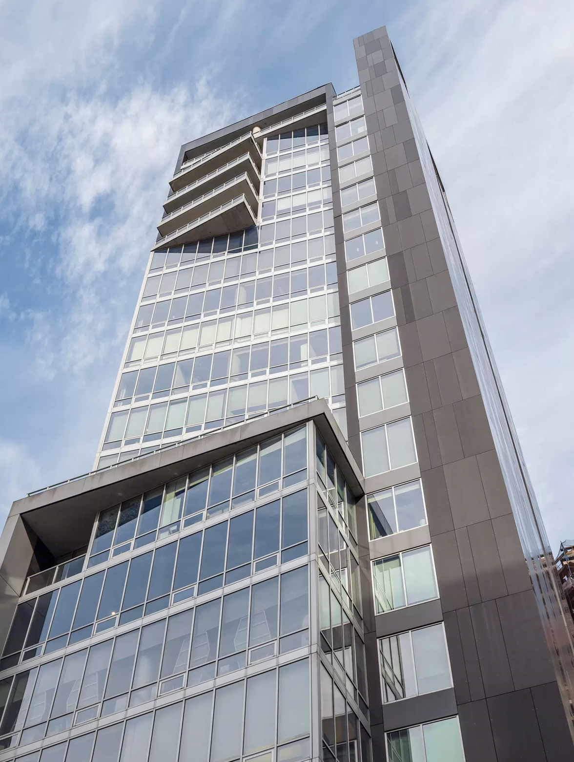 Modern glass high-rise building against a cloudy sky