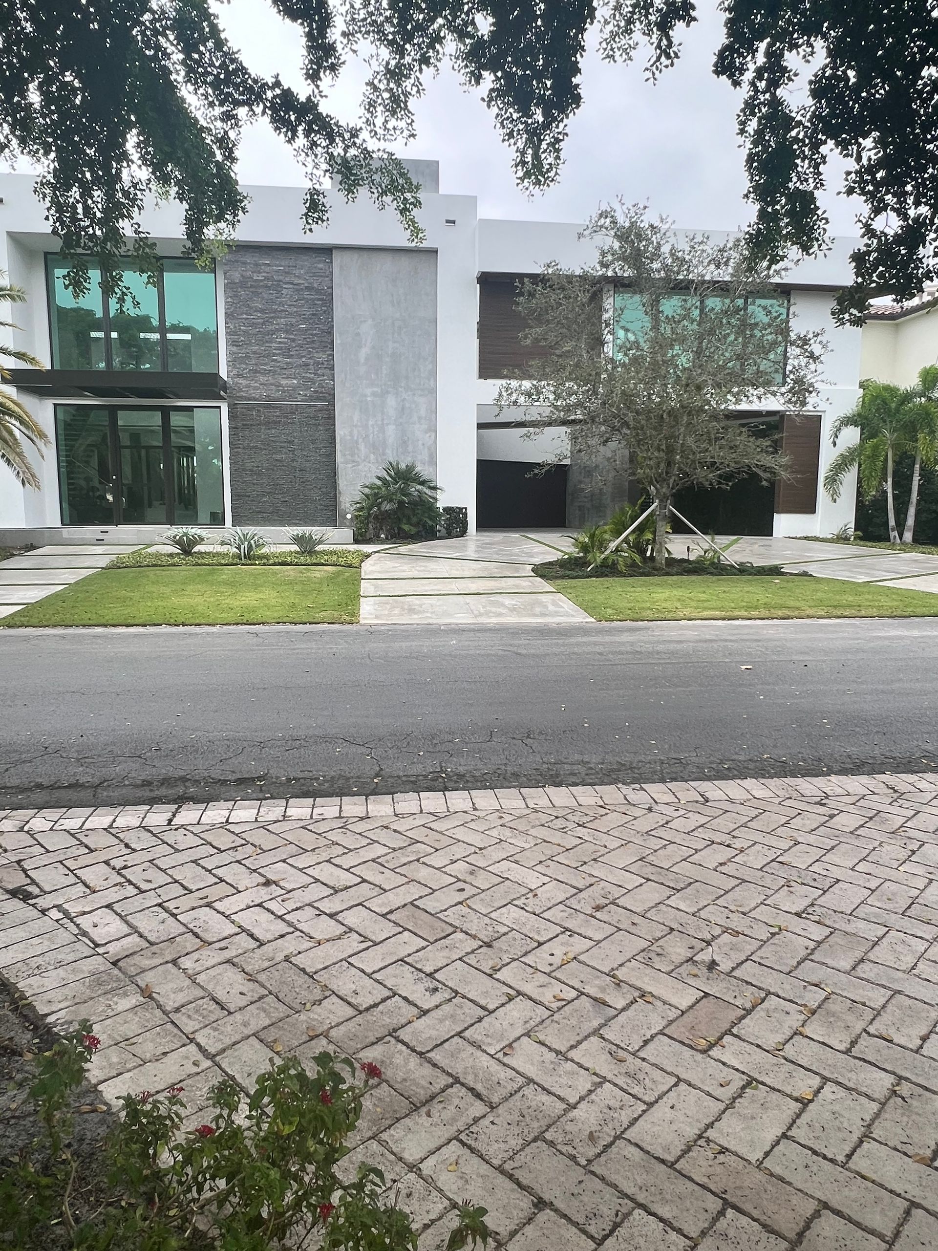 A large white house with a brick driveway in front of it