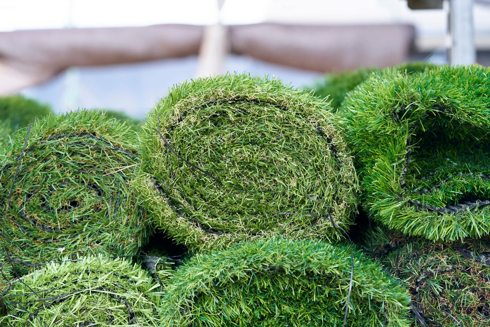 Fresh green sod rolls stacked together, showing healthy grass ready for landscaping use.