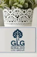 A desk features a white pot with a green plant next to a card with the blue 