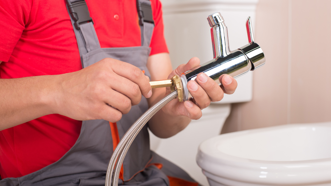 A plumber is fixing a faucet in a bathroom.