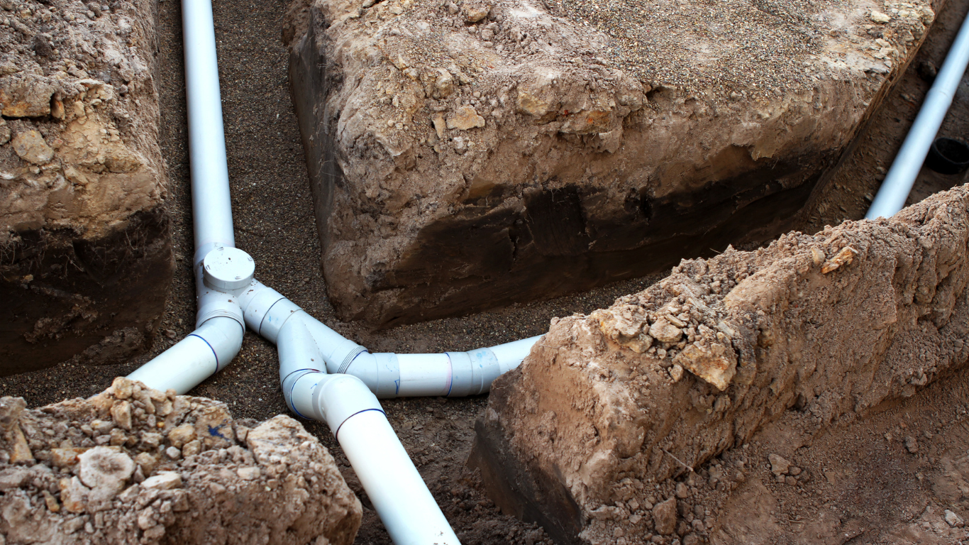 A bunch of pipes are laying in the dirt