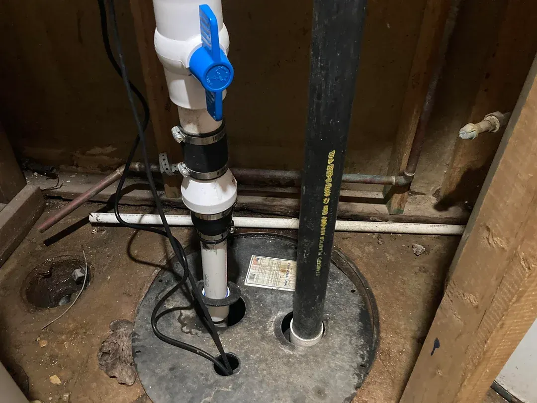 A close up of a basement pump with a blue valve.