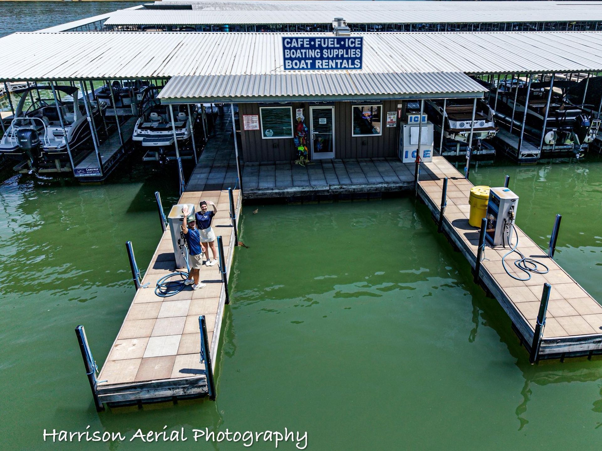 Marina fueling slips with boats and a marina store over green water.