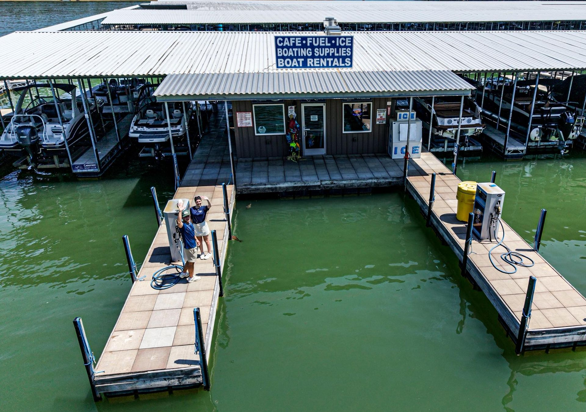 A floating marina dock with a small building and boats on green water