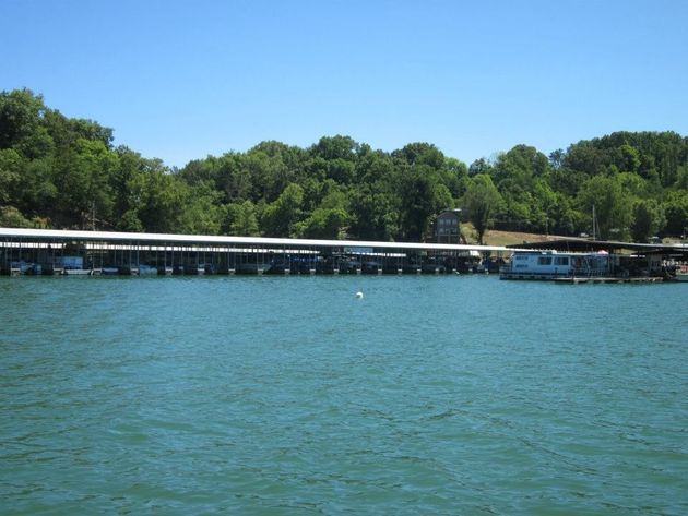 Explore Our Slips! Blue lake with a docked marina and tree-lined shore under a clear sky