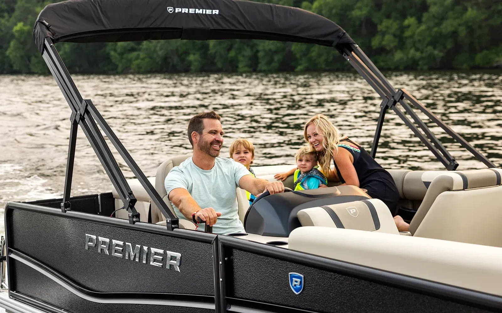 Family smiling in a pontoon boat on a calm lake with a black canopy