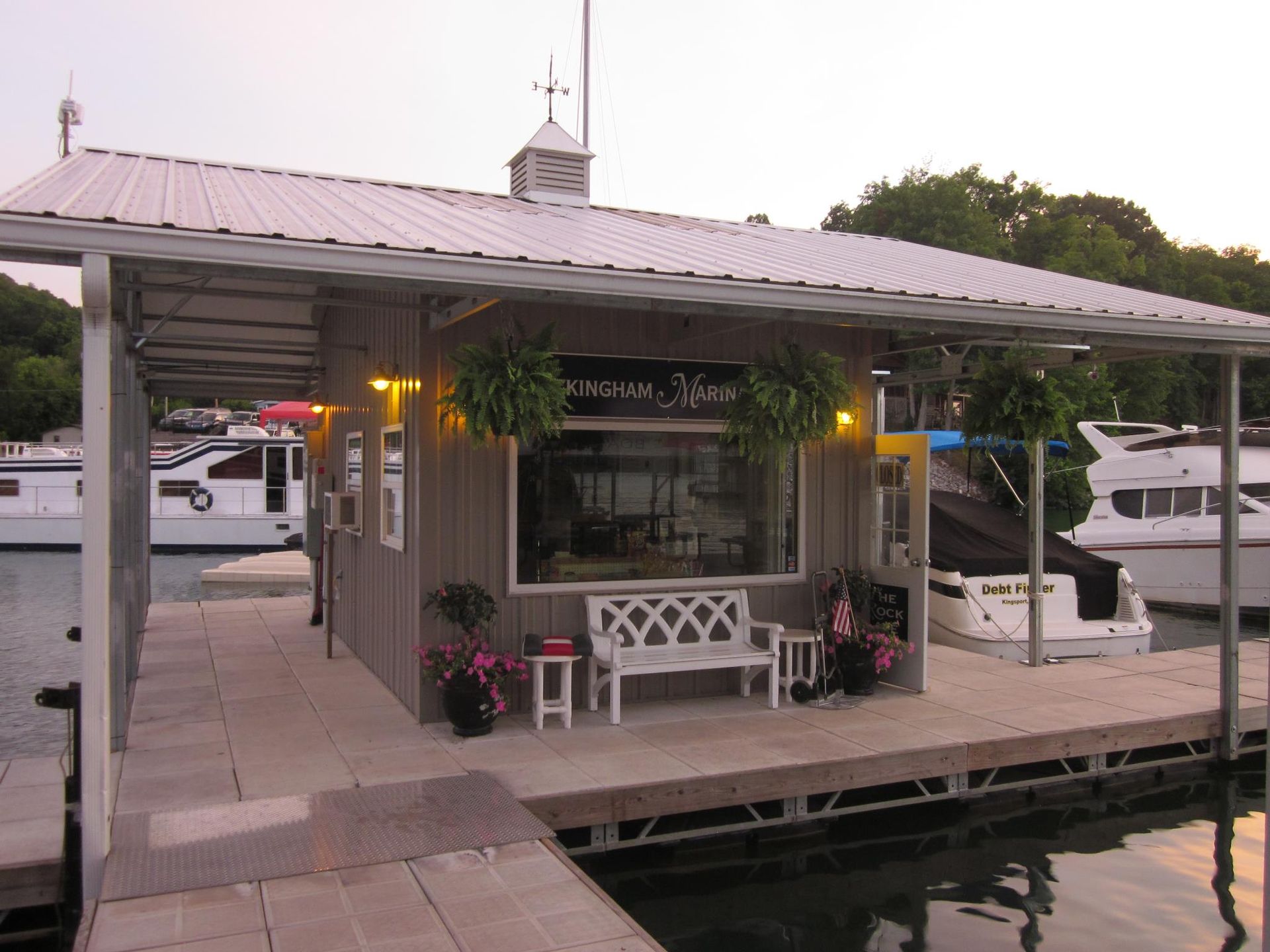 Small waterfront boathouse with a metal roof and docked boats at sunset
