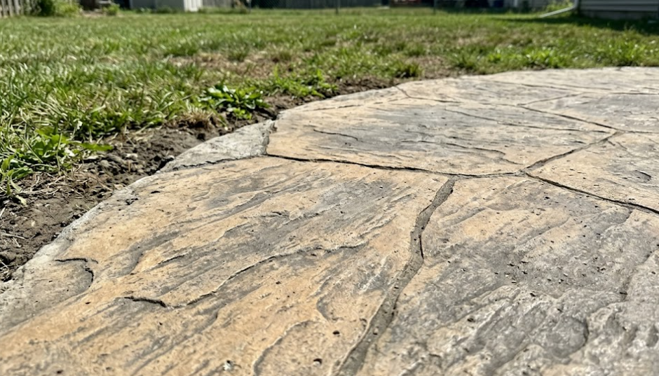 Close-up view of custom-stamped concrete designed to look like slate stone for a backyard patio.