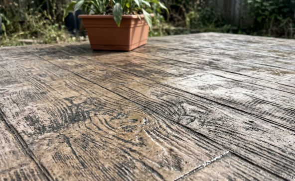 Close up detail of a decorative concrete patio stamped and colored to look like rustic wood planks.